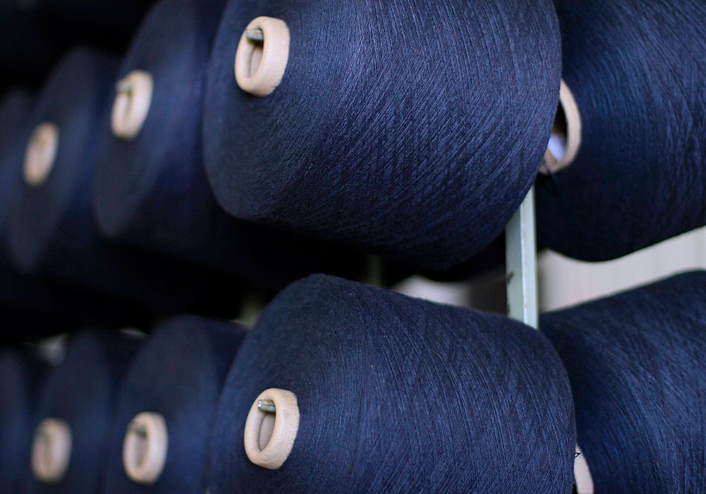Several blue cones of yarn on cone winding rack in preparation of the next step in weaving a heavy denim textile.