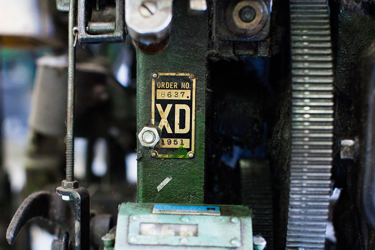 photograph showing a green Draper XD nameplate industrial shuttle loom near gears